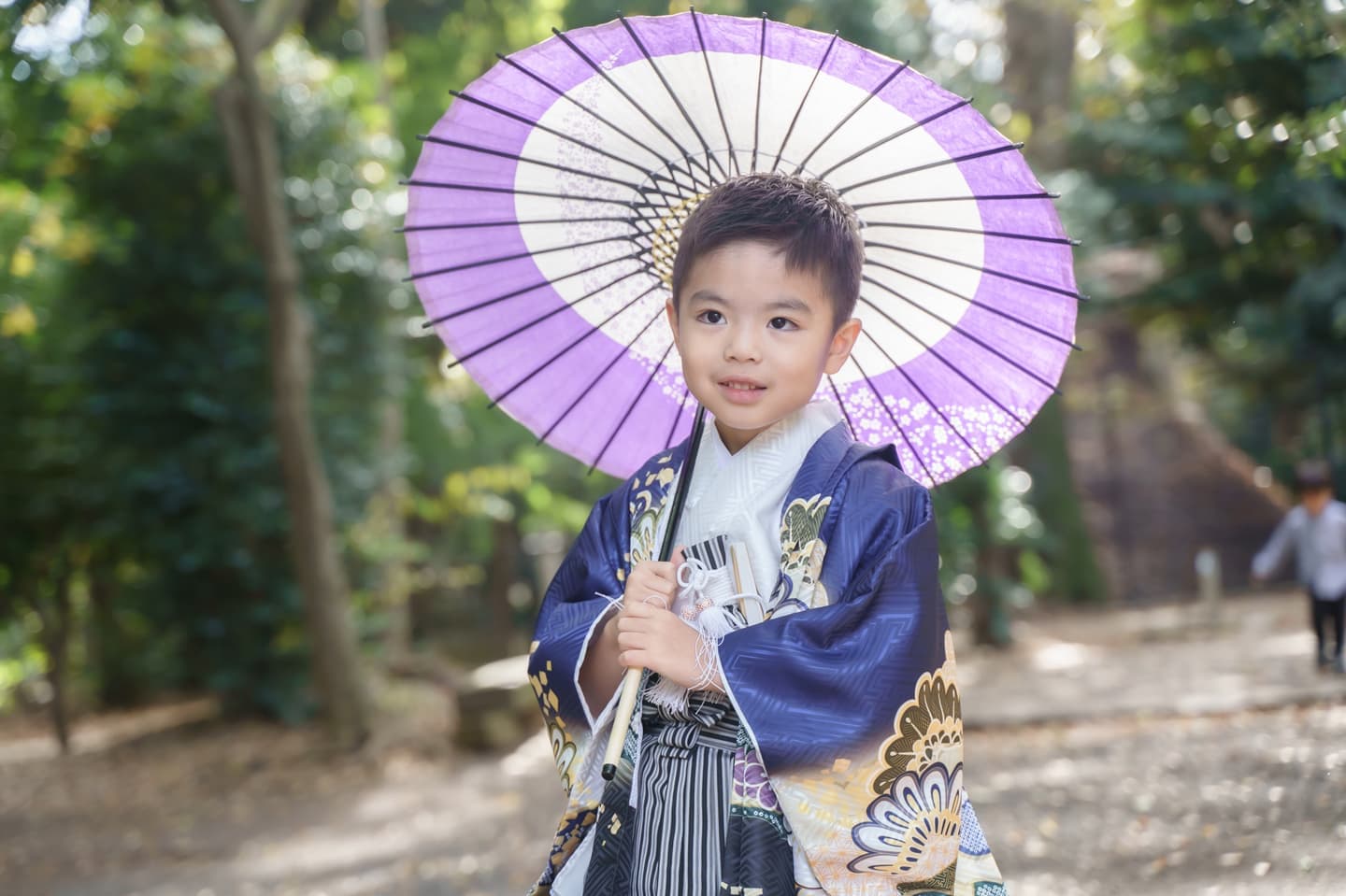 代々木八幡宮の参道で紫色の和傘を持って写真撮影している袴姿の男の子の写真