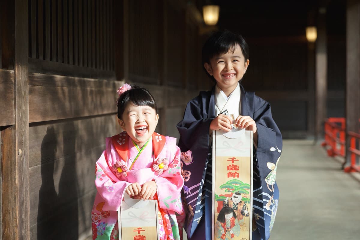 代々木八幡宮の七五三で、千歳飴を持ちながら笑顔の5歳袴姿の男の子と３歳お被布姿の女の子の写真