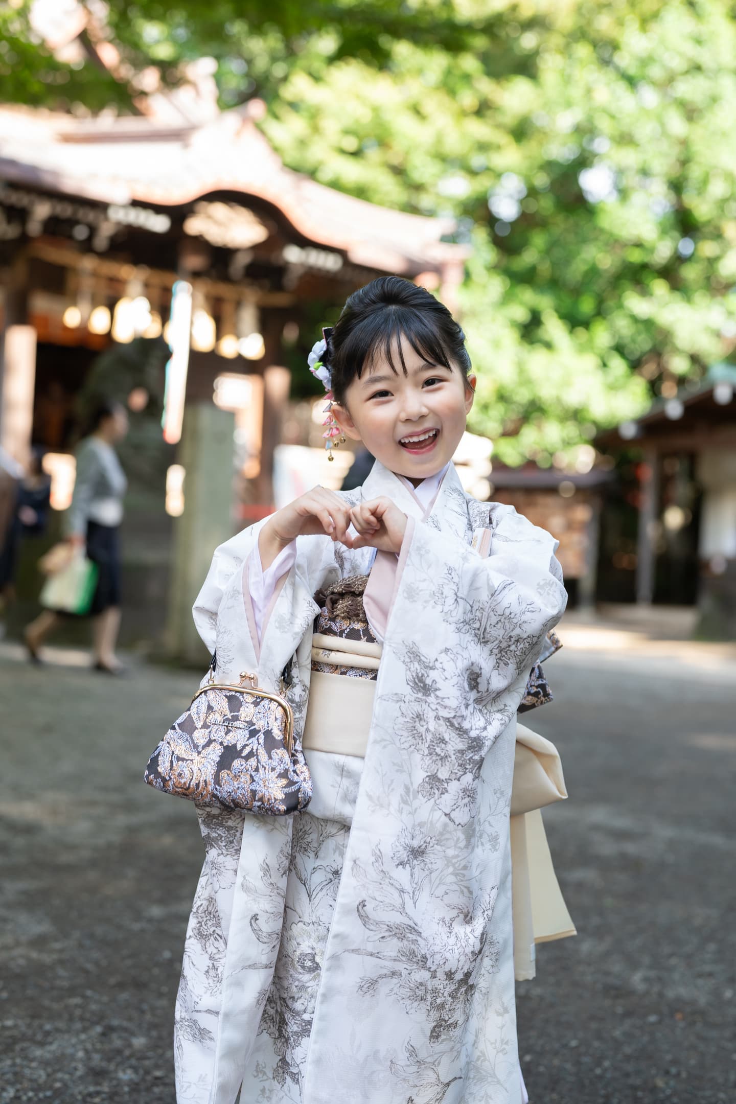 代々木八幡宮の社殿の前で手でハートマークを作る７歳七五三の女の子の写真