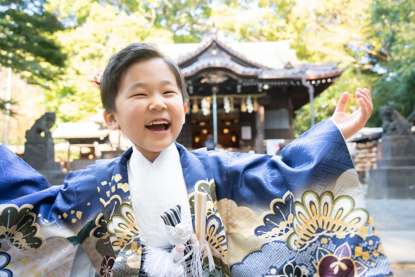 代々木八幡宮の社殿前で笑顔で楽しそうにはしゃぐ袴姿の5歳七五三の男の子の写真
