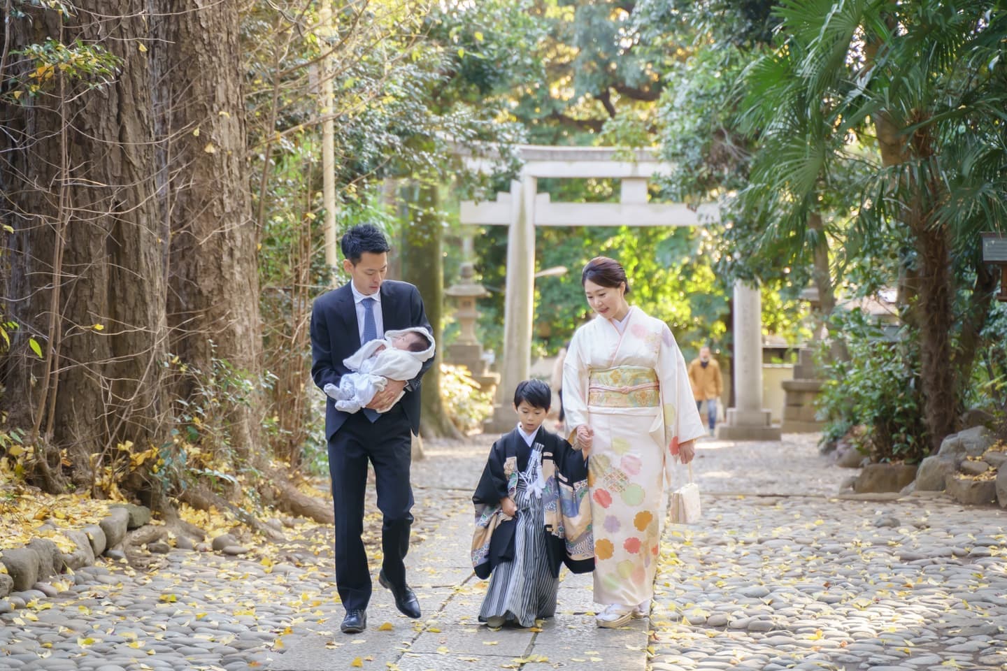 代々木八幡宮で七五三とお宮参りをしたご家族が手を繋いで参道を歩いている写真｜美容室スプラッシュ